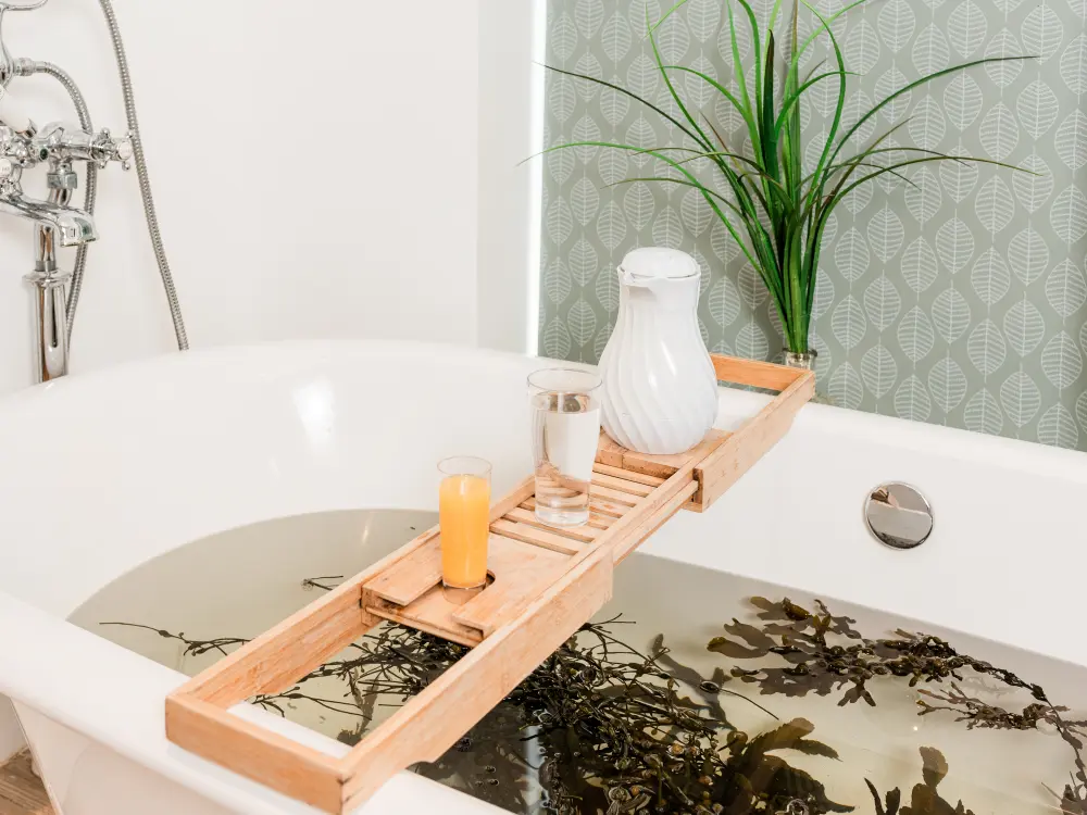 Wooden tray across seaweed bath holding a white jug and two drinks